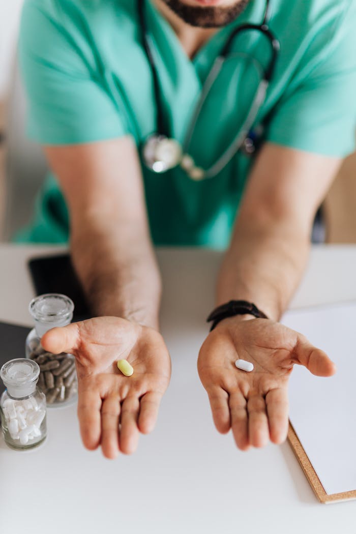 Crop doctor showing pills to patient in clinic
